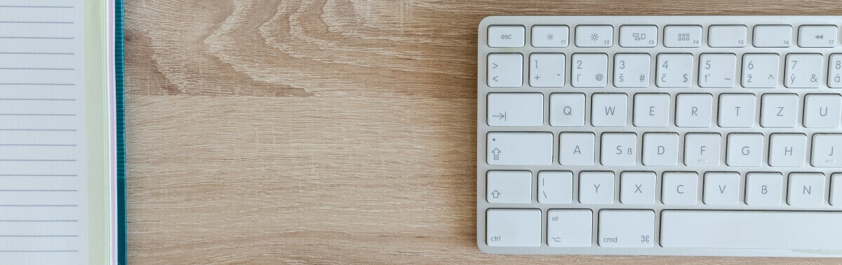 Mac keyboard on desk with note